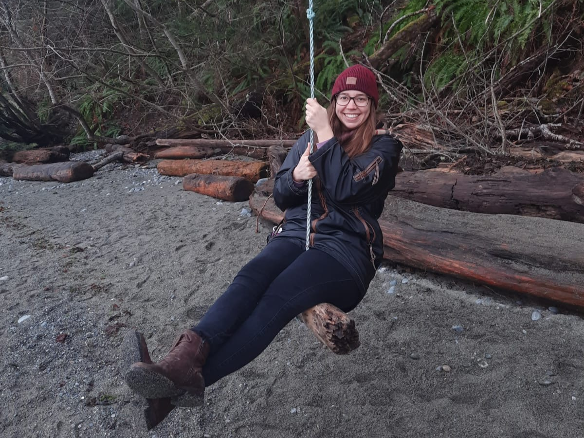 3 Kathi wearing a red beanie hat swinging on a swing